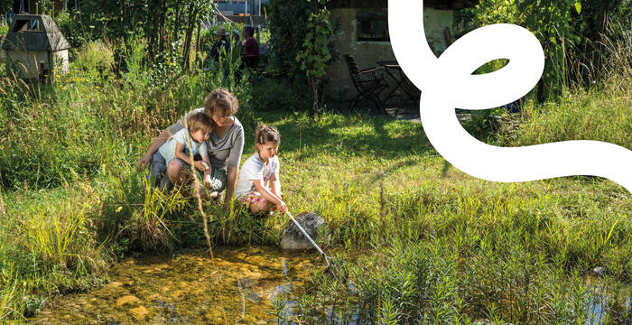 Familie mit zwei Kleinkindern keschert im naturnahen Garten
